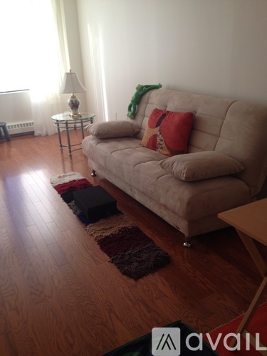 A living room with a beige couch and a brown rug.