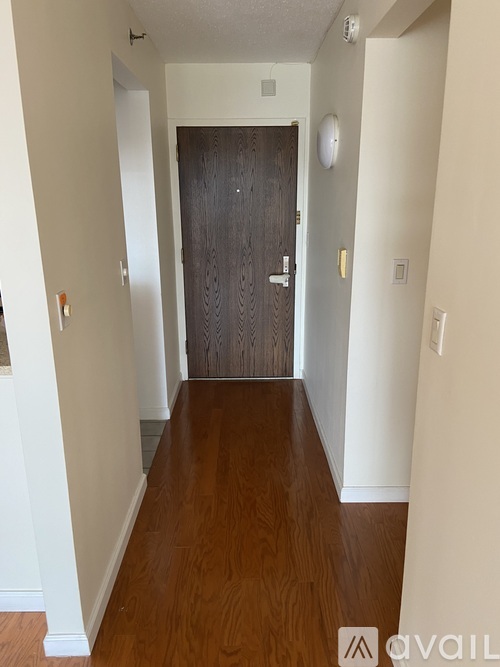 A hallway with a wooden floor and a dark brown door.