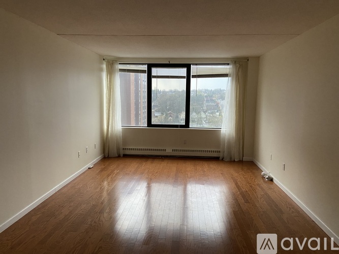 A room with wooden floors and a window overlooking a cityscape.