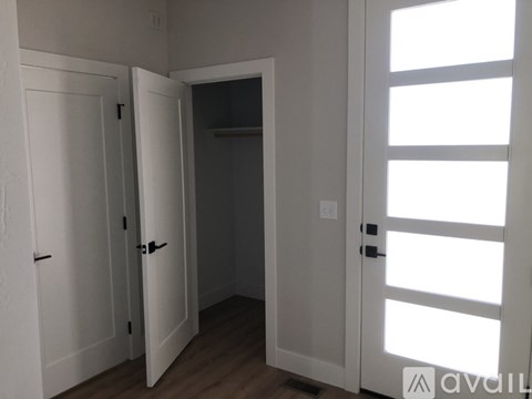 A white door with a black handle is open to a darker room.