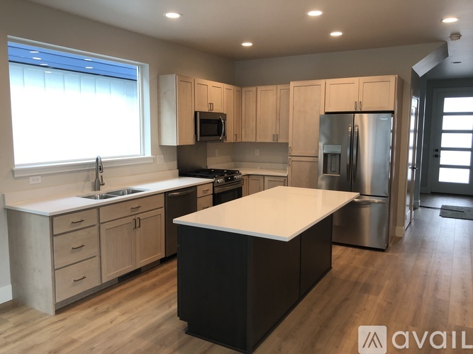 A kitchen with wooden cabinets and a black island.