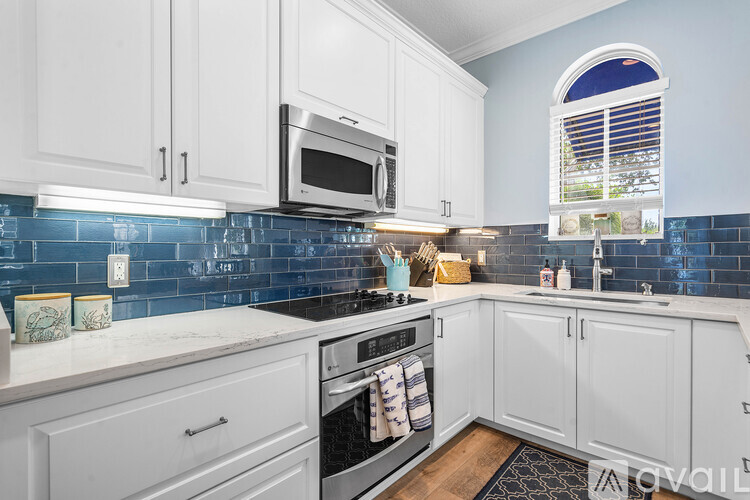 A kitchen with white cabinets and a blue tile backsplash.