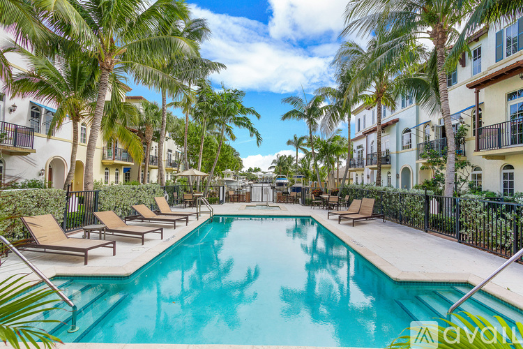 A pool surrounded by palm trees and lounge chairs.