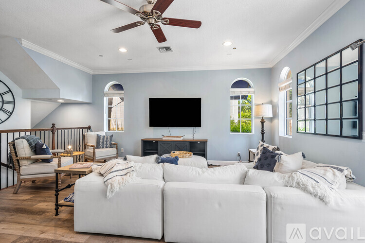 A living room with a white couch and a ceiling fan.