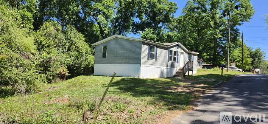 A small house is located on a grassy area next to a road.