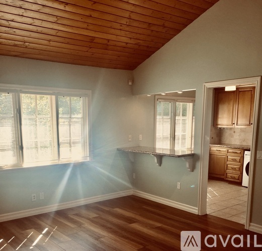 A room with wooden ceiling and floor with a window on the left side.