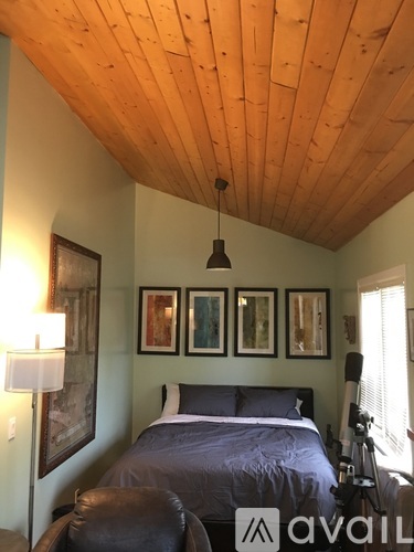 A bedroom with a bed, a chair, and pictures on the wall.