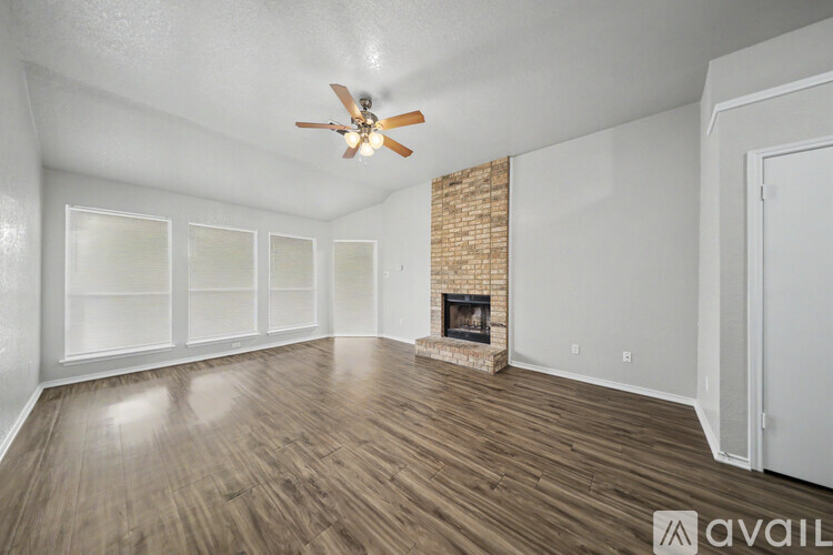 A spacious room with a fireplace and wood flooring.
