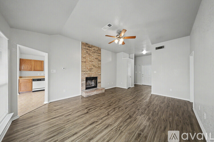 A spacious living room with wood flooring and a brick fireplace.