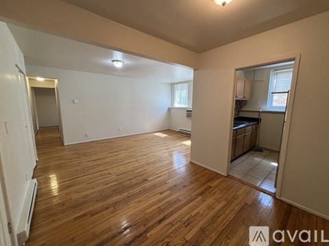 A room with wooden flooring and a small kitchenette in the corner.