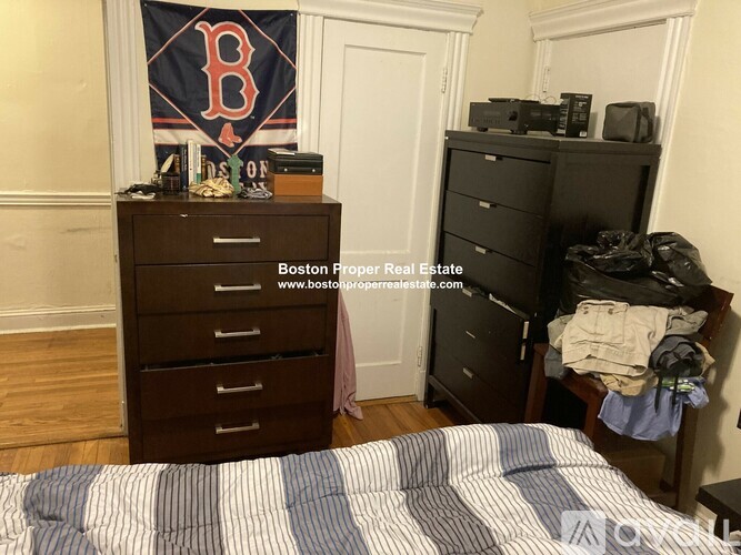 A bedroom with a bed, dresser, and a Boston Red Sox flag.