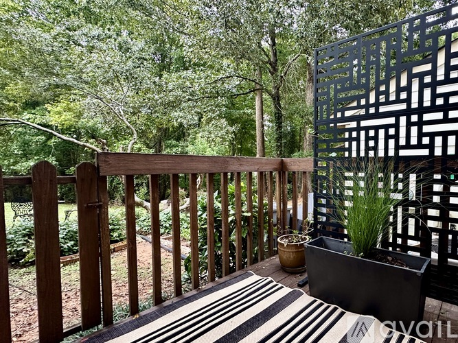 A wooden deck with a black and white striped rug and a wooden railing.
