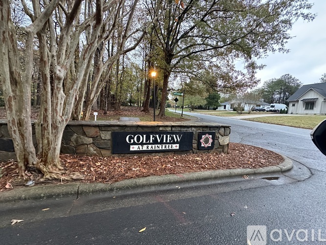 A sign that says Golfview Apartments stands in front of a row of trees.