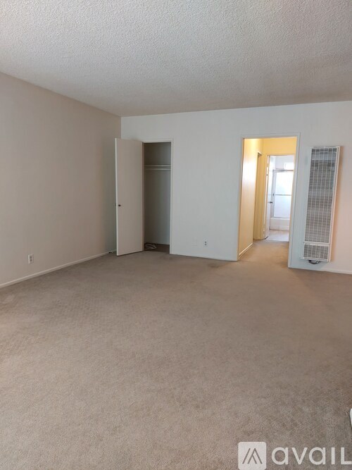 A spacious empty room with beige carpeting and white walls.