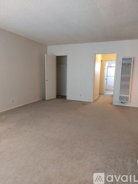 A spacious empty room with beige carpeting and white walls.