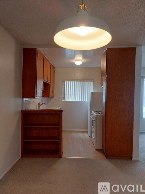 A small, empty room with a wooden cabinet and a light hanging from the ceiling.