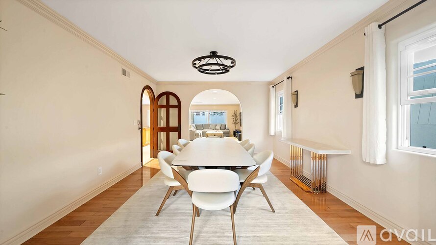 A dining room with a white table and chairs.