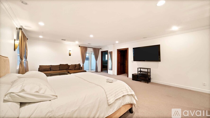 A bedroom with a large bed and a flat screen TV mounted on the wall.