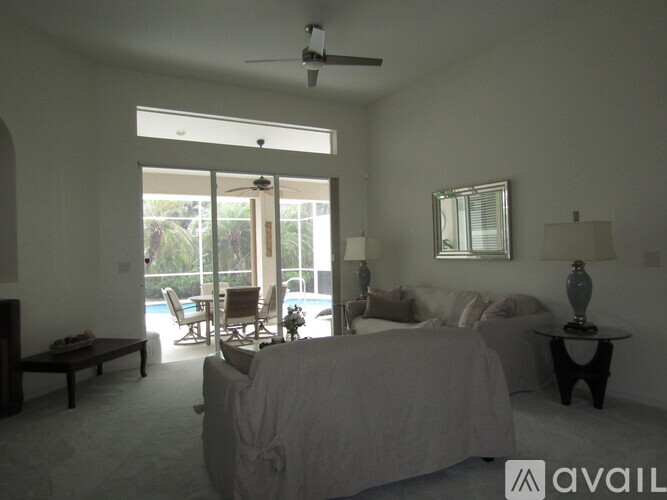 A bedroom with a large bed and a balcony overlooking a pool.