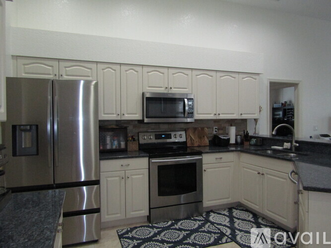 A kitchen with a stainless steel refrigerator and white cabinets.