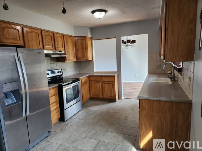 A kitchen with wooden cabinets and a stainless steel refrigerator.