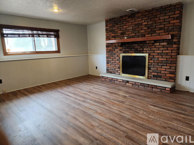 A room with a brick fireplace and wooden flooring.
