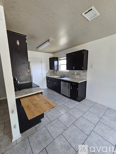 A kitchen with black cabinets and a wooden island.