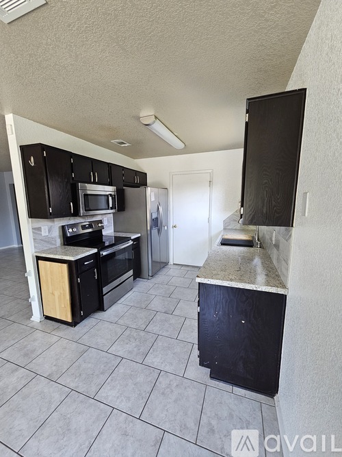 A kitchen with black cabinets and a microwave above the stove.
