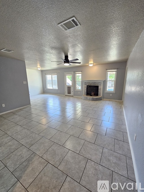 A spacious room with a fireplace and a ceiling fan.