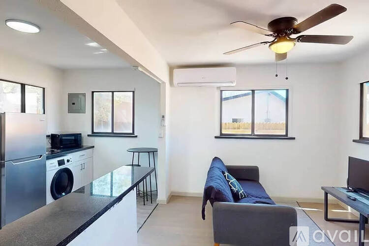A modern living room with a blue couch and a fan.