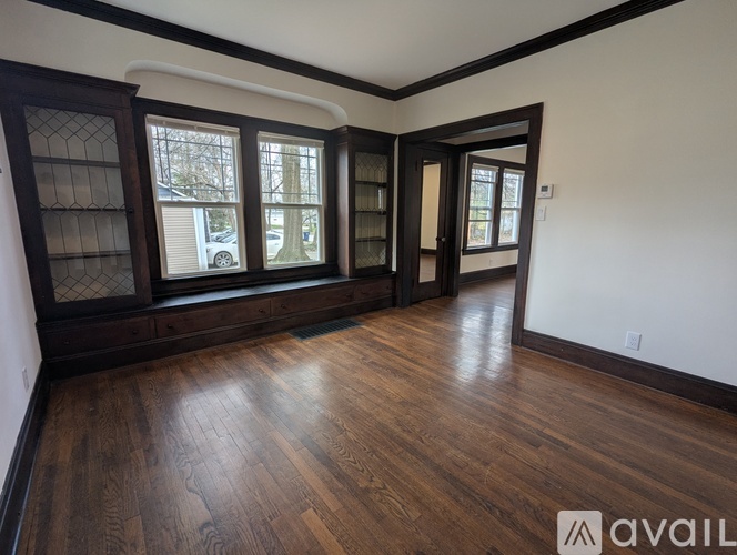 A room with wooden floors and a large window with a view of a street.