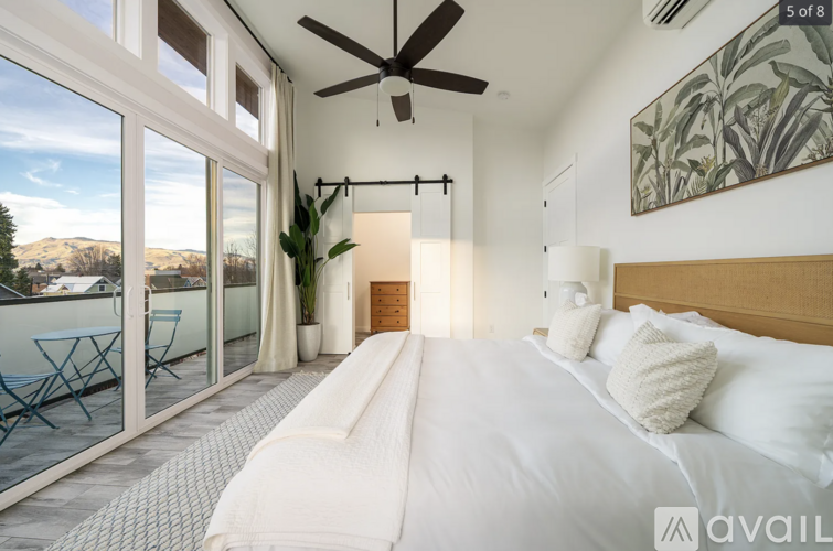 A bedroom with a large bed and a balcony overlooking a mountainous landscape.