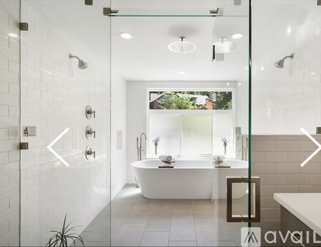 A modern bathroom with a white tub and a glass shower stall.