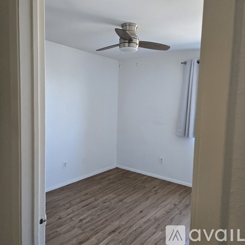 A room with a ceiling fan and wooden flooring.