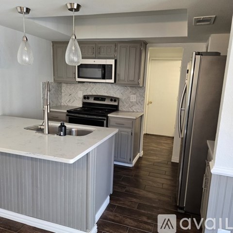 A kitchen with a white counter top and a stainless steel refrigerator.