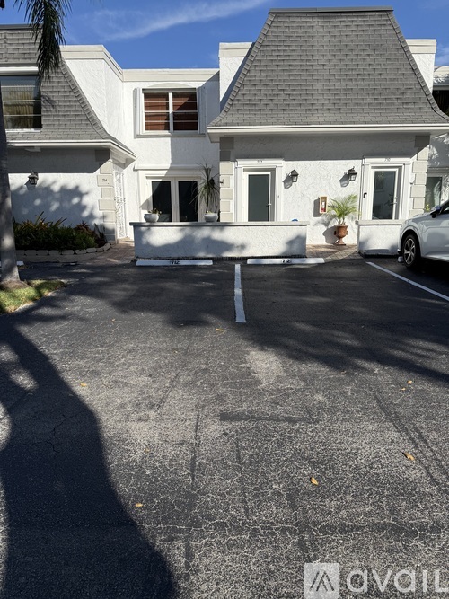 A white house with a grey roof and a car parked in front.