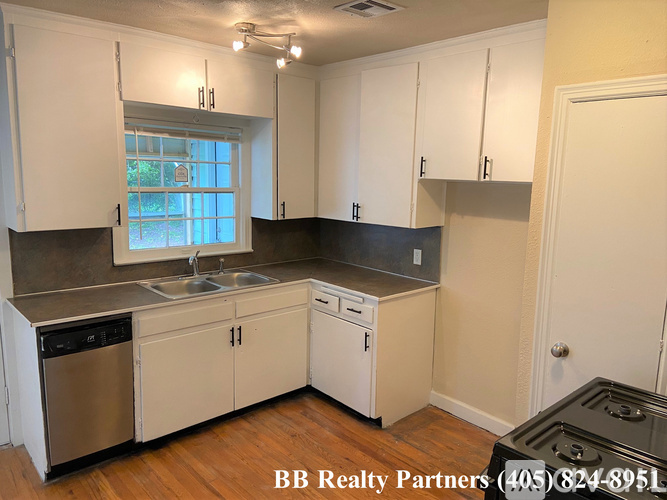 A kitchen with white cabinets and a window.