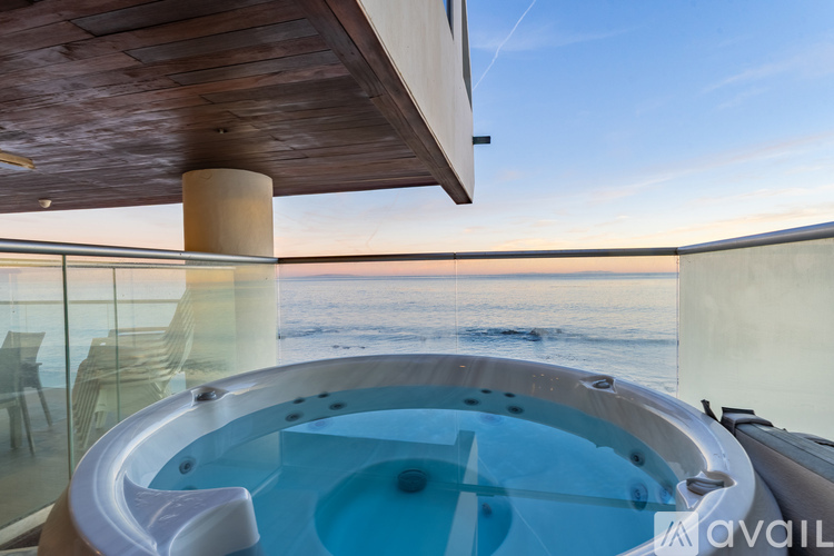A hot tub is situated on a balcony overlooking the ocean.