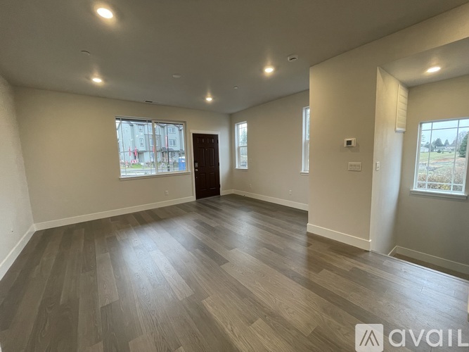 A spacious room with wooden flooring and a large window.