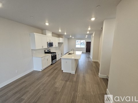 A spacious kitchen with white cabinets and a wooden floor.