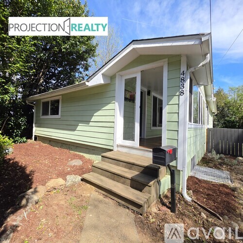 A small green house with a porch and a mailbox.