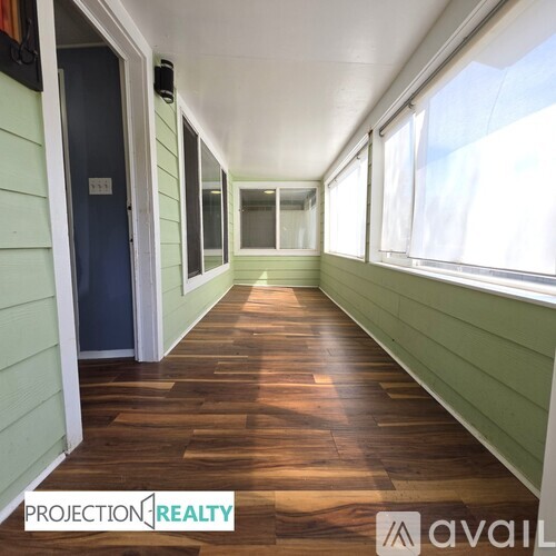 A long hallway with wood floors and green walls.