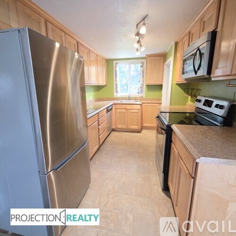 A kitchen with a stainless steel refrigerator and wooden cabinets.