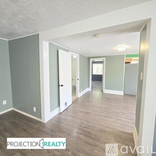 A spacious room with wood flooring and white walls.