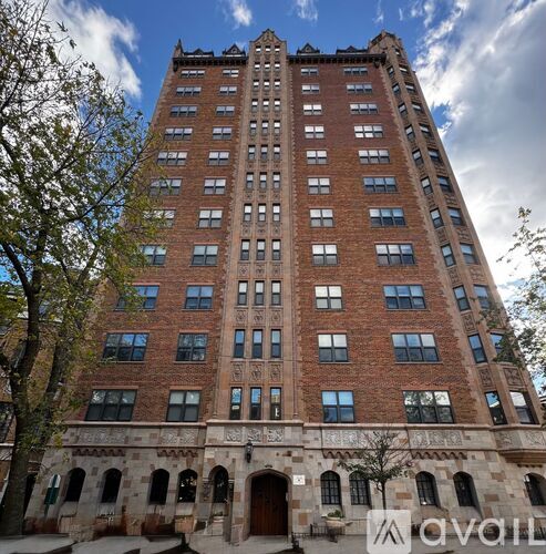 A tall red brick building with many windows and a stone base.