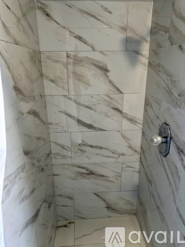 A shower with marble tiles and a wall-mounted faucet.