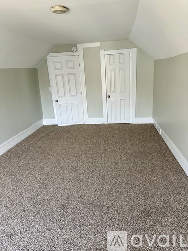 A room with carpeted floor and two white doors.