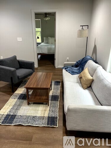 A living room with a grey couch, a wooden coffee table and a rug.