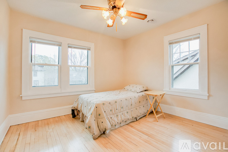 A bedroom with a bed, a ceiling fan, and two windows.