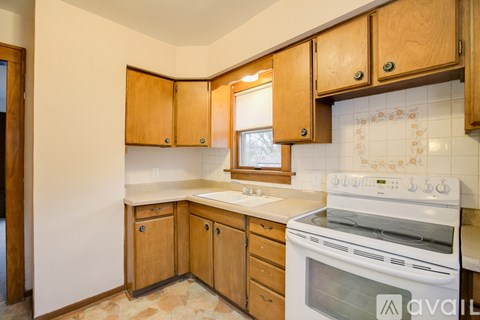A kitchen with wooden cabinets and a white stove top oven.